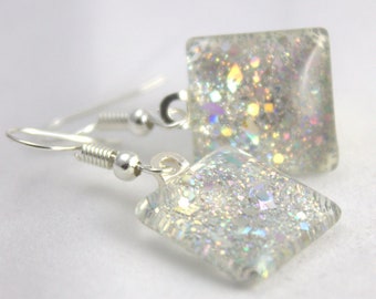 May include: Silver dangle earrings with iridescent glitter encased in clear square glass.