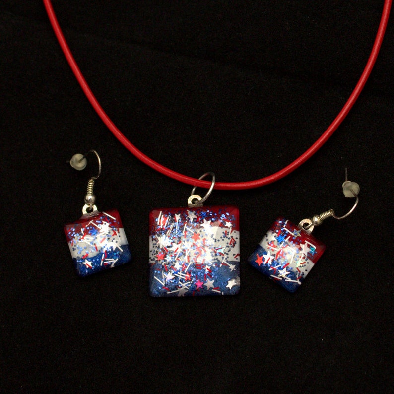 Peut inclure: Un collier et des boucles d'oreilles assortis en paillettes rouge, blanc et bleu. Le collier a un pendentif carr&eacute; avec des paillettes rouge, blanc et bleu et des &eacute;toiles. Les boucles d'oreilles sont &eacute;galement carr&eacute;es et ont des paillettes rouge, blanc et bleu et des &eacute;toiles.