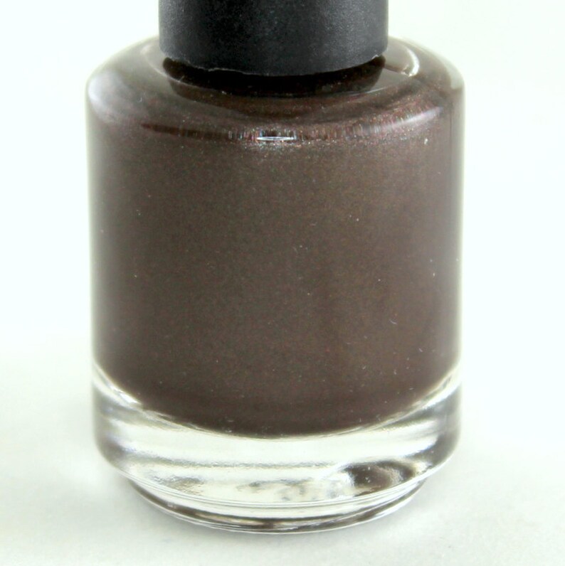 K&ouml;nnte beinhalten: Eine Flasche dunkelbraunen Nagellacks mit einer durchsichtigen Glasflasche und einem schwarzen Deckel.