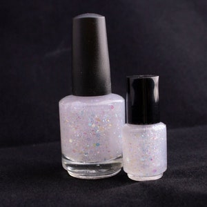 May include: Two bottles of clear nail polish with a white iridescent glitter finish. The bottles have black caps.