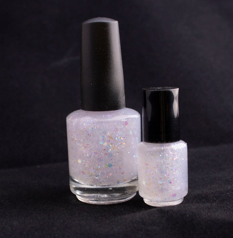 May include: Two bottles of clear nail polish with a white iridescent glitter finish. The bottles have black caps.