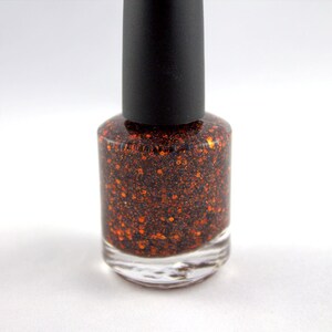 May include: A bottle of orange glitter nail polish with a black cap.