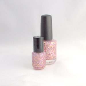 May include: Two bottles of pink glitter nail polish with black caps. The bottles are different sizes.