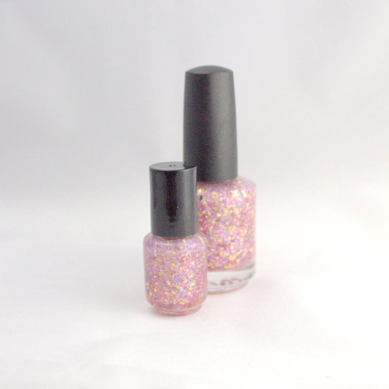 May include: Two bottles of pink glitter nail polish with black caps. The bottles are different sizes.