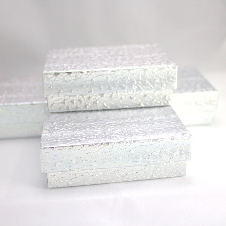 May include: Three silver gift boxes stacked on top of each other. The boxes have a textured, cracked finish.
