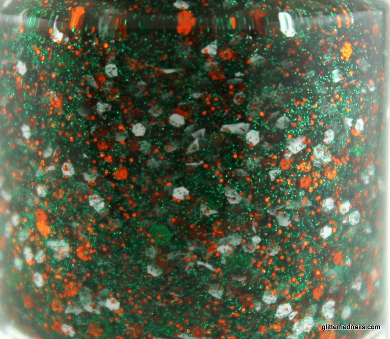 May include: A close-up of a green nail polish bottle with orange and white glitter.