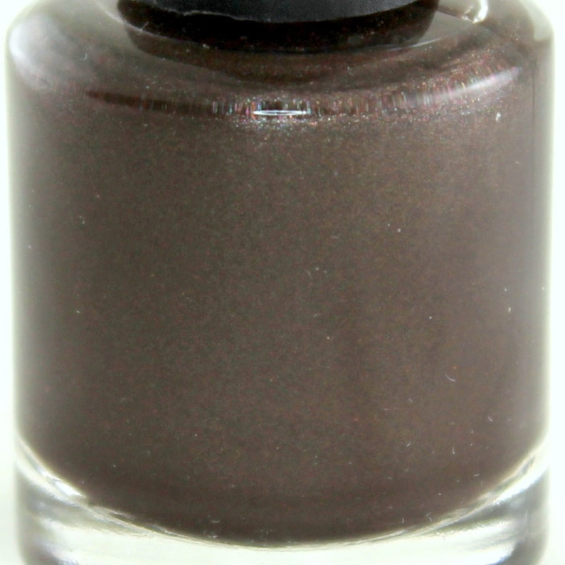 K&ouml;nnte beinhalten: Nahaufnahme einer Flasche dunkelbraunen Nagellacks mit Metallic-Finish.