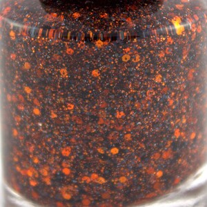 May include: Close-up of a dark brown nail polish with orange and silver glitter.