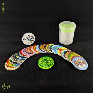 May include: A collection of colorful pogs, including a green "SLAMMIN JAMMS" pog and a white pog with "CUSTOM POGS .COM" text. A clear plastic container holds a stack of pogs. The pogs are arranged in an arc.