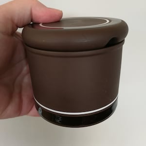 May include: A brown ceramic sugar bowl with a white rim and a matching lid. The lid has a small spout for pouring.