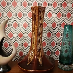 Może przedstawiać: Brązowy i kremowy ceramiczny wazon o geometrycznym wzorze. Wazon ma szeroką podstawę i wąską szyjkę.