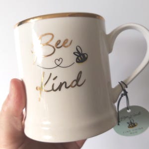 May include: A set of three ceramic mugs with a speckled, matte finish. The mugs are in cream, light grey, and dark grey. Each mug has a simple, minimalist design and a rounded handle.