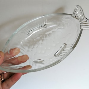 May include: A clear glass serving dish shaped like a fish with an etched grape design.