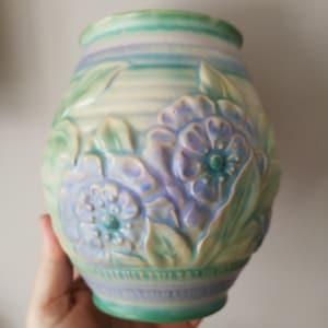 Könnte beinhalten: Eine Keramikvase mit einem blauen, grünen und weißen Blumendesign. Die Vase hat einen runden Körper und eine breite Öffnung.
