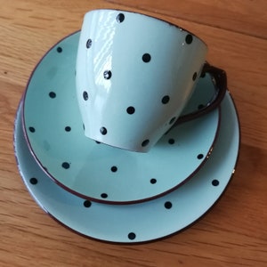 May include: A light blue teacup and saucer set with black polka dots. The set is made of ceramic and has a vintage style.