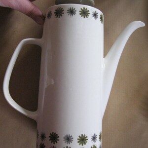 May include: White ceramic coffee pot with a brown lid and a green and gray floral pattern.
