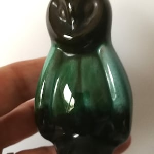 以下が含まれることがあります： 光沢のある小さなセラミック製のフクロウの置物。フクロウの頭は濃い茶色で、濃い緑色の体に変わります。置物は手で持たれており、そのサイズと形状を示しています。装飾品です。