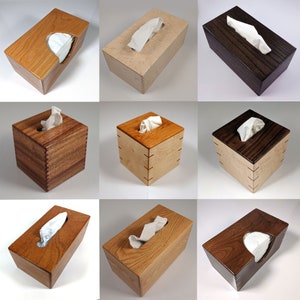 May include: Nine different wooden tissue box covers in various wood stains. The tissue boxes are all rectangular and have a slot for the tissues to be pulled out. The wood grain is visible on all of the boxes.