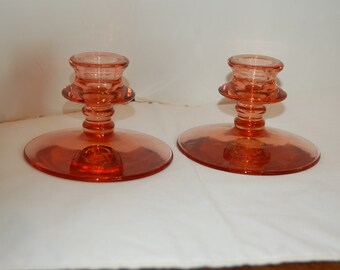 Peut inclure: Deux bougeoirs en verre vintage de couleur pêche clair. Les bougeoirs ont une base large et un seul gobelet à bougie.