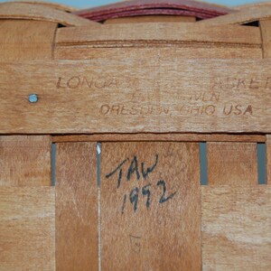 May include: Close-up of a wooden basket with a label that reads "Longaberger Basket Co. Dresden, Ohio USA". The basket is marked with the date "1972".