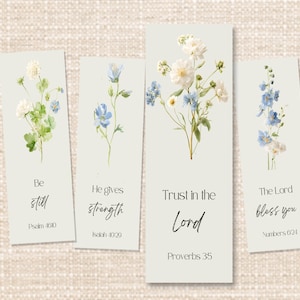 Puede incluir: Cuatro marcapáginas rectangulares con diseños florales en acuarela. Cada marcapáginas presenta un arreglo floral diferente en tonos blancos, azules y verdes. El texto incluye citas inspiradoras: "Estate quieto", "Él da fuerza", "Confía en el Señor" y "El Señor te bendiga."