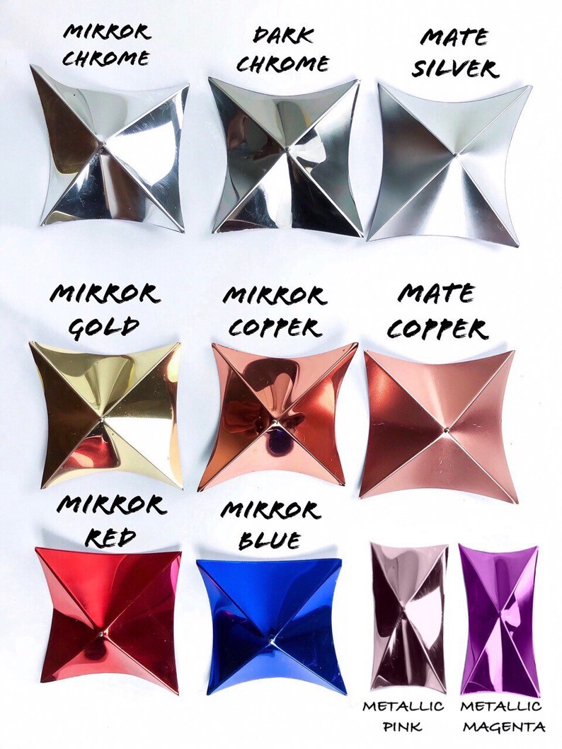Pu&ograve; includere: Dodici piccole piastrelle metalliche decorative di forma quadrata, in vari colori e finiture. Le piastrelle sono disposte in tre file di quattro. La fila superiore presenta cromo a specchio, cromo scuro e argento opaco. La seconda fila presenta oro a specchio, rame a specchio e rame opaco. La terza fila presenta rosso a specchio, blu a specchio, rosa metallizzato e magenta metallizzato.