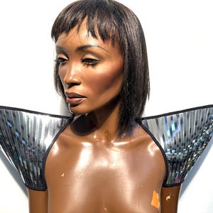 May include: A silver and black shoulder piece with a mirrored finish. The piece is made of small, rectangular tiles that are sewn together.