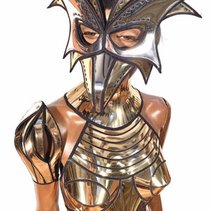 May include: A silver and black metallic costume with a bird-like mask. The costume features a geometric design with a high neckline and a fitted bodice.