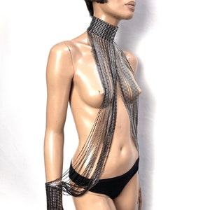 Op de afbeelding: Een zilveren en zwarte strass choker met lange strengen strass die aan de voorkant naar beneden hangen. De ketting wordt gedragen door een mannequin.