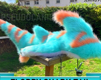 May include: A digital download sewing pattern for a floppy shark tail. The tail is made of turquoise blue and peach colored faux fur. The pattern is available for purchase on Etsy.