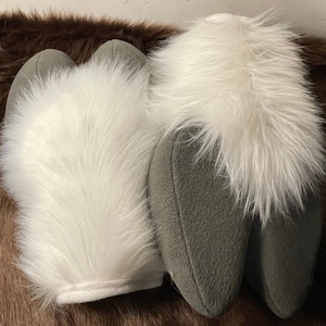 Puede incluir: Un par de patas de mano de piel blanca con tela gris en la parte posterior. Las patas est&aacute;n dise&ntilde;adas para parecer patas de animales.