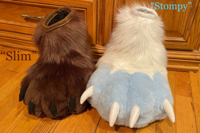 May include: Two furry paw-shaped hand puppets, one brown with black claws labeled "Slim" and one white with blue claws and a white tip labeled "Stompy".