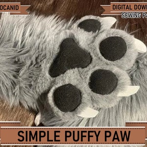 Pode incluir: Uma pata de pele sintética cinzenta com almofadas pretas e garras brancas. O texto "PSEUDOCANID" está no canto superior esquerdo e "DIGITAL DOWNLOAD SEWING PATTERN" no canto superior direito. O texto "SIMPLE PUFFY PAW" está na parte inferior.