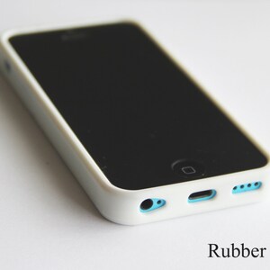 Pu&ograve; includere: Una custodia per telefono in gomma bianca con schermo nero. La custodia ha accenti azzurri attorno alle porte e un bordo bianco. Il testo "Rubber Case" &egrave; visibile in basso.