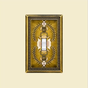May include: A rectangular light switch plate featuring a metallic bronze finish with a beaded border. The center displays a symmetrical floral pattern in shades of gold, cream, and brown, surrounding a single white toggle switch.
