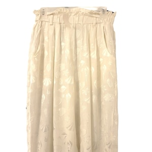 May include: White high-waisted pants with a wide leg and a seashell pattern.
