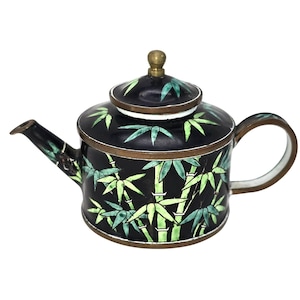 May include: A black teapot featuring a hand-painted green bamboo pattern, a brass-colored metal rim, a matching lid with a small brass-colored knob, and a curved handle. The spout is also decorated with green bamboo leaves against a black background.