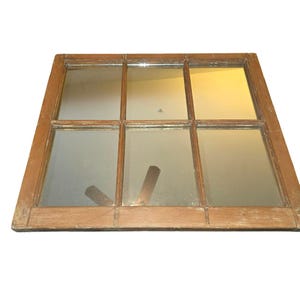 May include: A rectangular wall mirror featuring a weathered brown wooden frame with a grid pattern that divides the reflective surface into six individual panes. The wood shows signs of age and wear, providing a textured appearance to the frame.