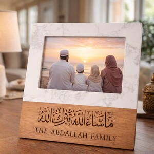 May include: A wooden photo frame with a marble-look border. The frame displays a family photo at the beach during sunset. The bottom of the frame has Arabic calligraphy and the text "THE ABDALLAH FAMILY".
