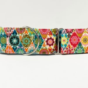 May include: A colorful dog collar with a geometric pattern in shades of pink, green, blue, and orange. The collar has a silver buckle and is made of durable fabric.