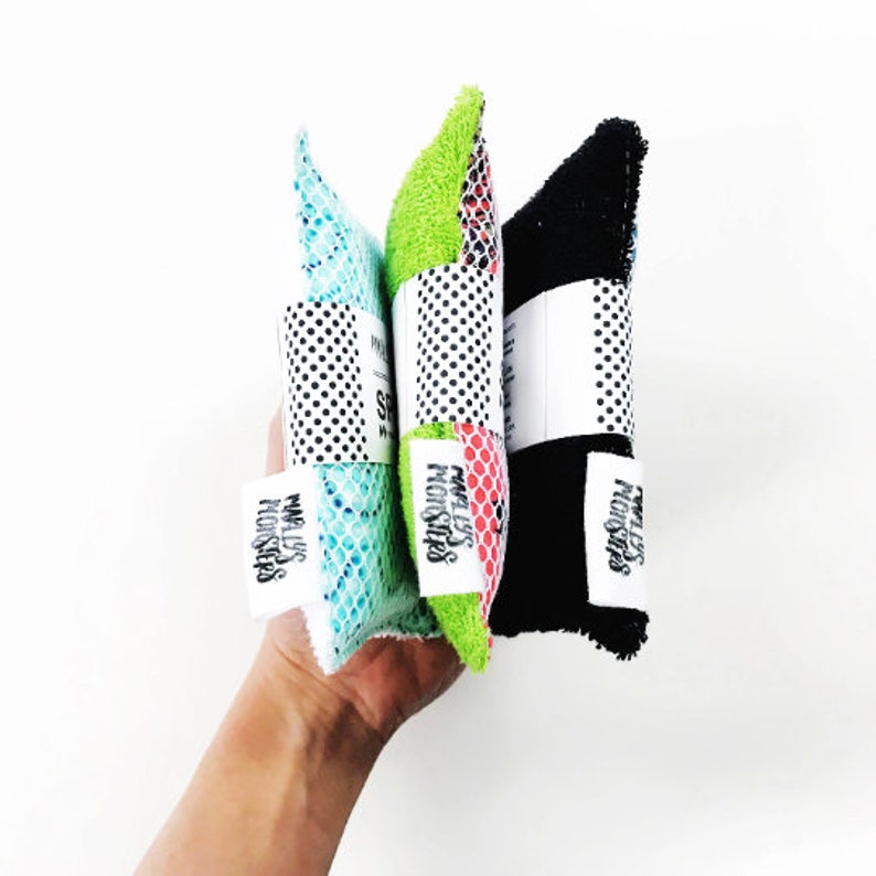 May include: Three colorful kitchen scrubbers with a black and white polka dot pattern and the text "Messy Monsters" on each. The scrubbers are green, blue, and red.