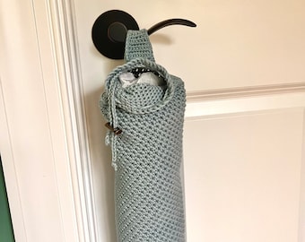 May include: A light blue crocheted bag hanging on a door handle. The bag is made with a textured stitch and has a wooden button.