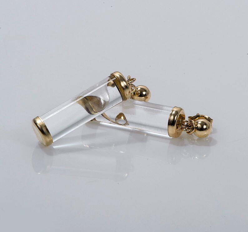 May include: A pair of gold and clear crystal earrings. The earrings are shaped like small tubes with a gold ball at the bottom.