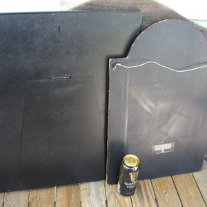 May include: Two black framed signs with a Guinness logo on one of the signs. A can of Guinness beer is in the foreground.