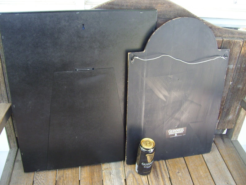 May include: Two black framed signs with a Guinness logo on one of the signs. A can of Guinness beer is in the foreground.