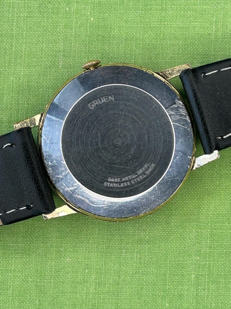 Vintage 1960s Gruen Precision watch.  Black leather band.  Running, serviced, keeps time, working.  Gold plated case with black dial