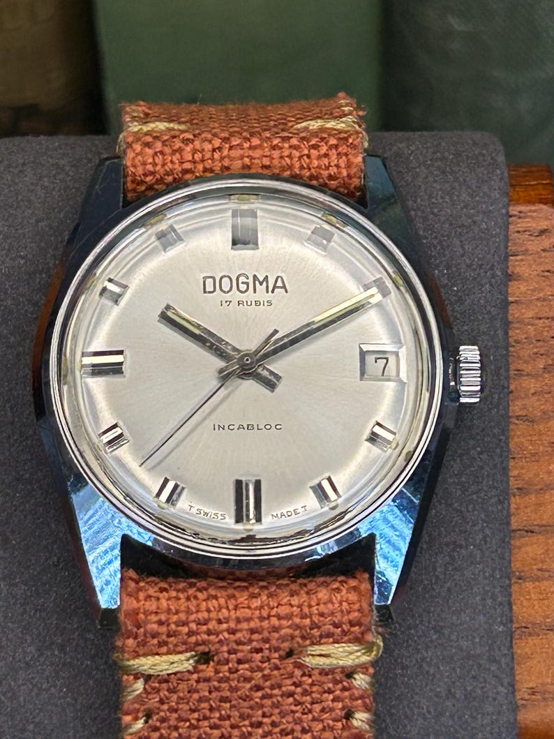 Vintage watch Dogma swiss watch with silver case and sweep seconds dial.  Has date window. New custom orange band and silver crown. Running, serviced, keeps time, working.