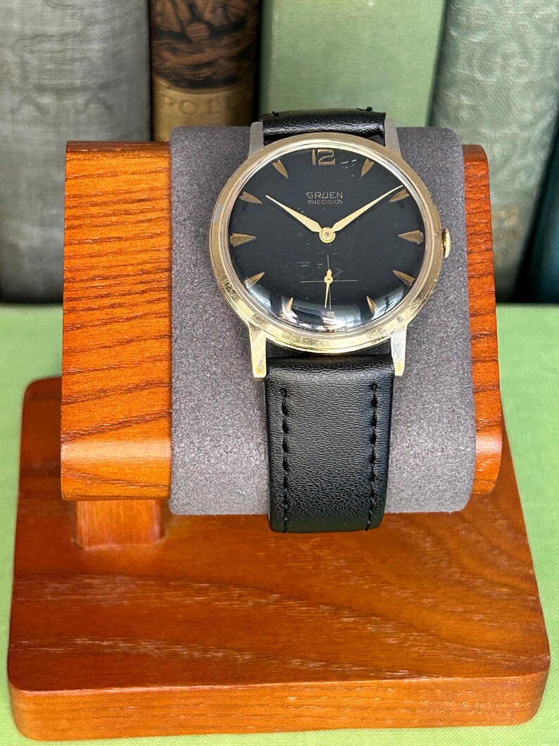 Vintage 1960s Gruen Precision watch.  Black leather band.  Running, serviced, keeps time, working.  Gold plated case with black dial