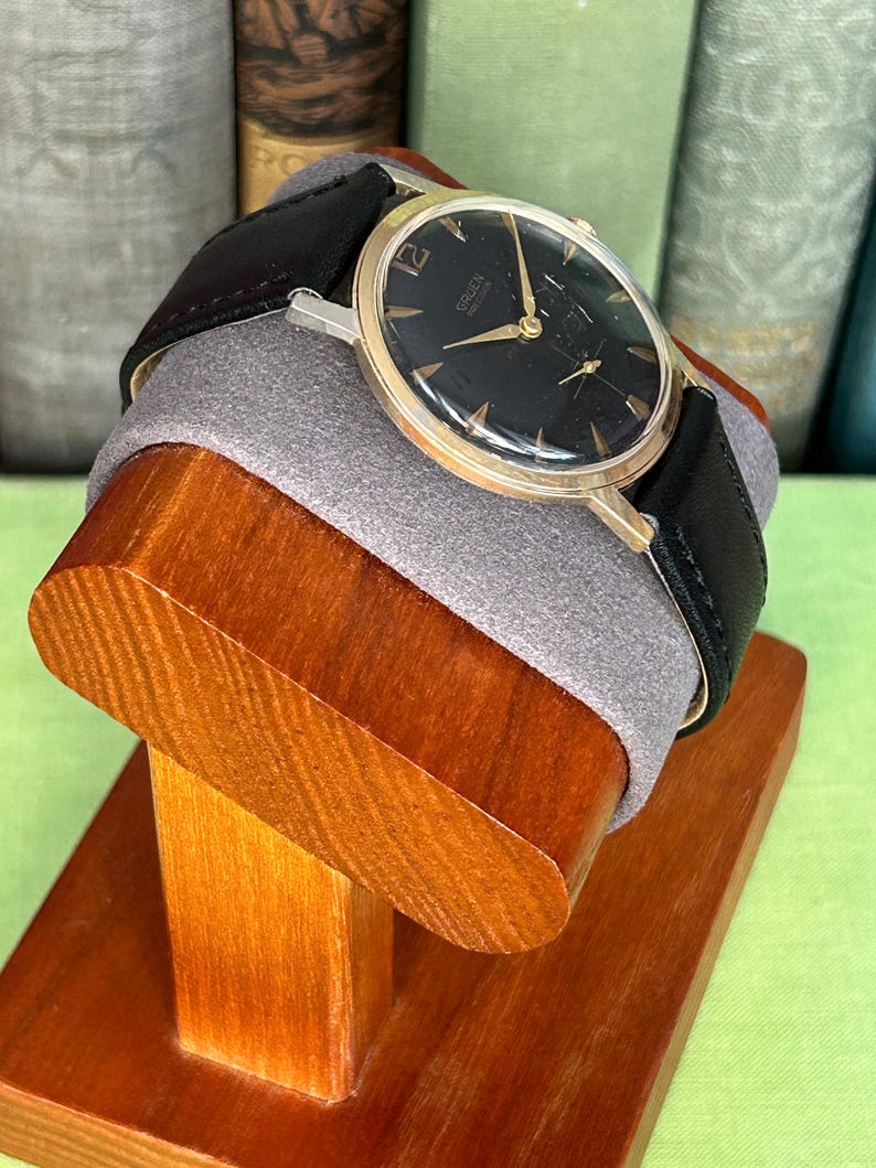 Vintage 1960s Gruen Precision watch.  Black leather band.  Running, serviced, keeps time, working.  Gold plated case with black dial