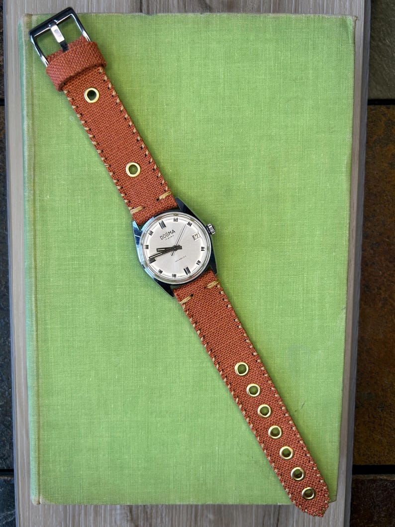 Vintage watch Dogma swiss watch with silver case and sweep seconds dial.  Has date window. New custom orange band and silver crown. Running, serviced, keeps time, working.